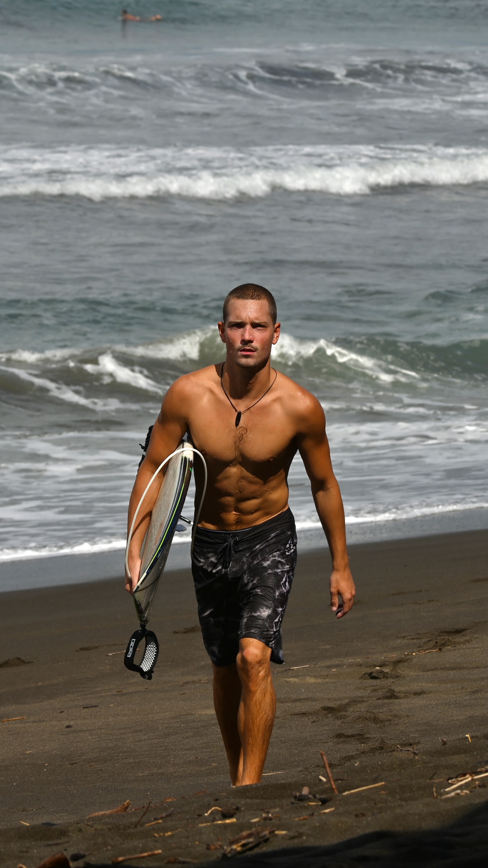 Tony walking on the beach with surfboard